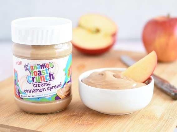Cinnamon Toast Crunch cinnamon spread jar next to a bowl with an apple dipped in the spread
