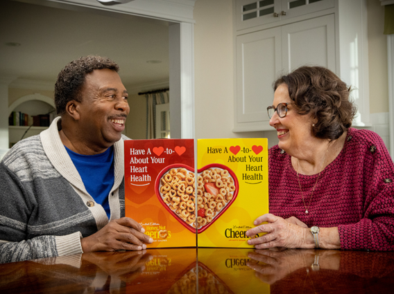 Leslie David Baker and Phyllis Smith smiling with their Cheerios Happy Hearts boxes