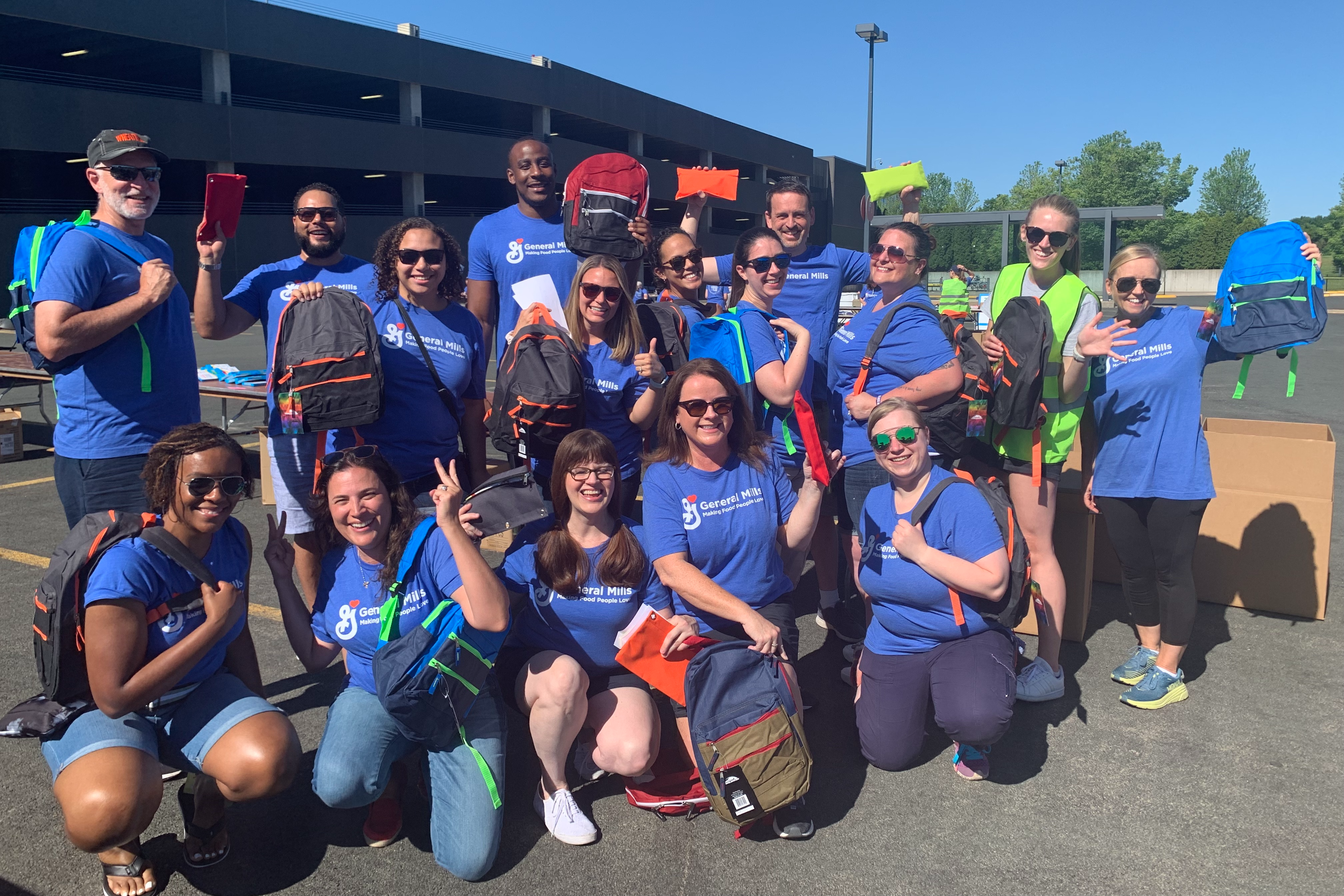 A group of employees holding backpacks up